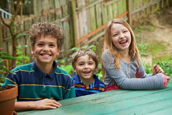 Kim's grandkids sitting at the backyard picnic table.