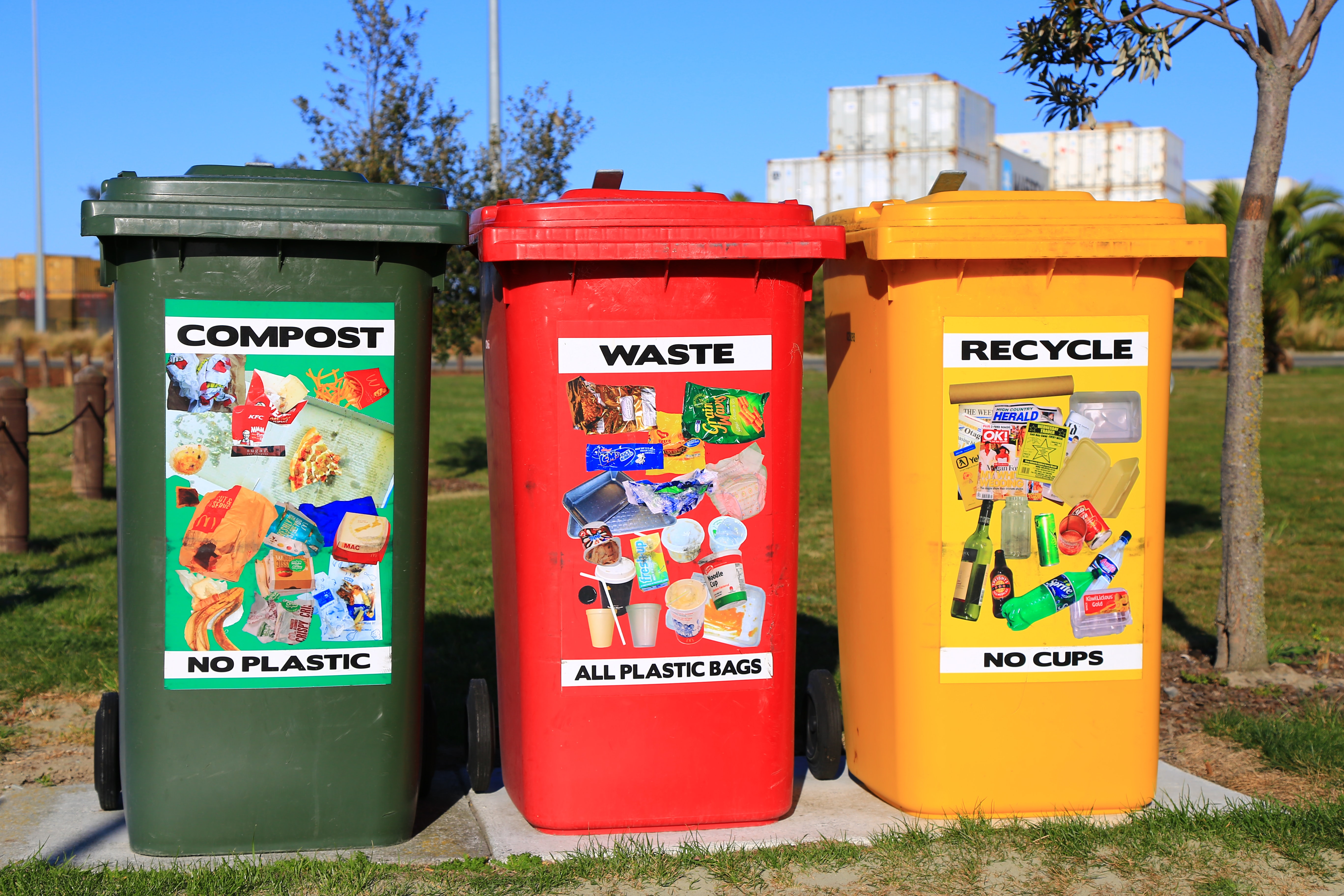 A green bin for compost, a red bin for waste, and a yellow bin for recycle