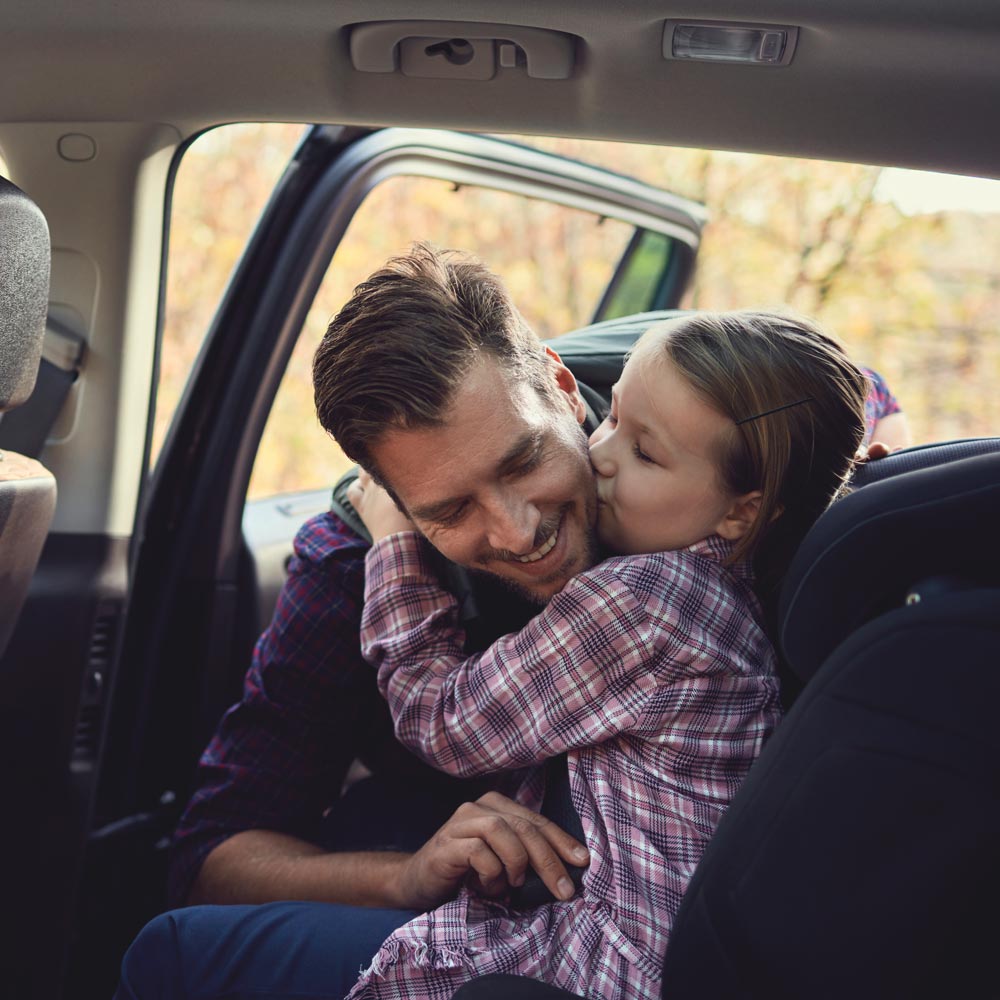 father buckling in daughter